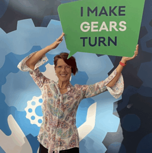 Miriam Romais holding up a sign that says "I Make Gears Turn"